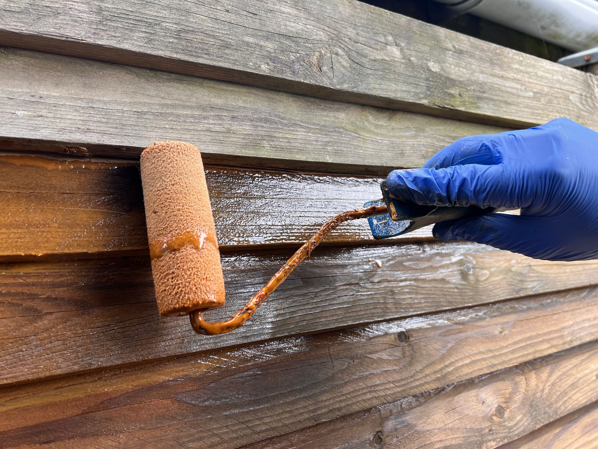 Man painting wooden fence